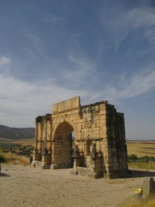 Ancient ruins stand under a blue sky.